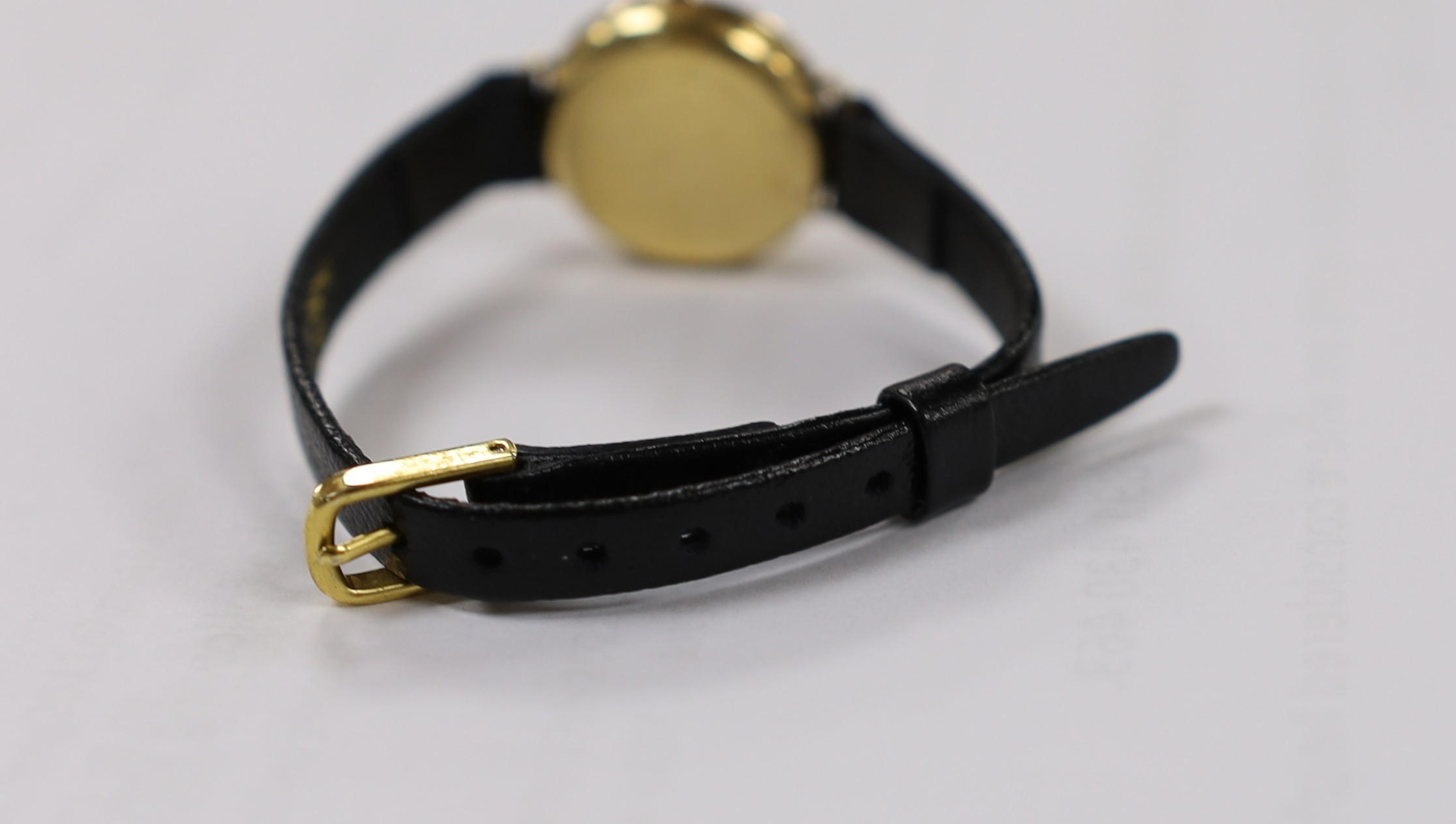 A lady's 18k manual wind wrist watch, with diamond set bezel and dial with baton numerals (a.f.), on a leather strap, lacks winding crown.